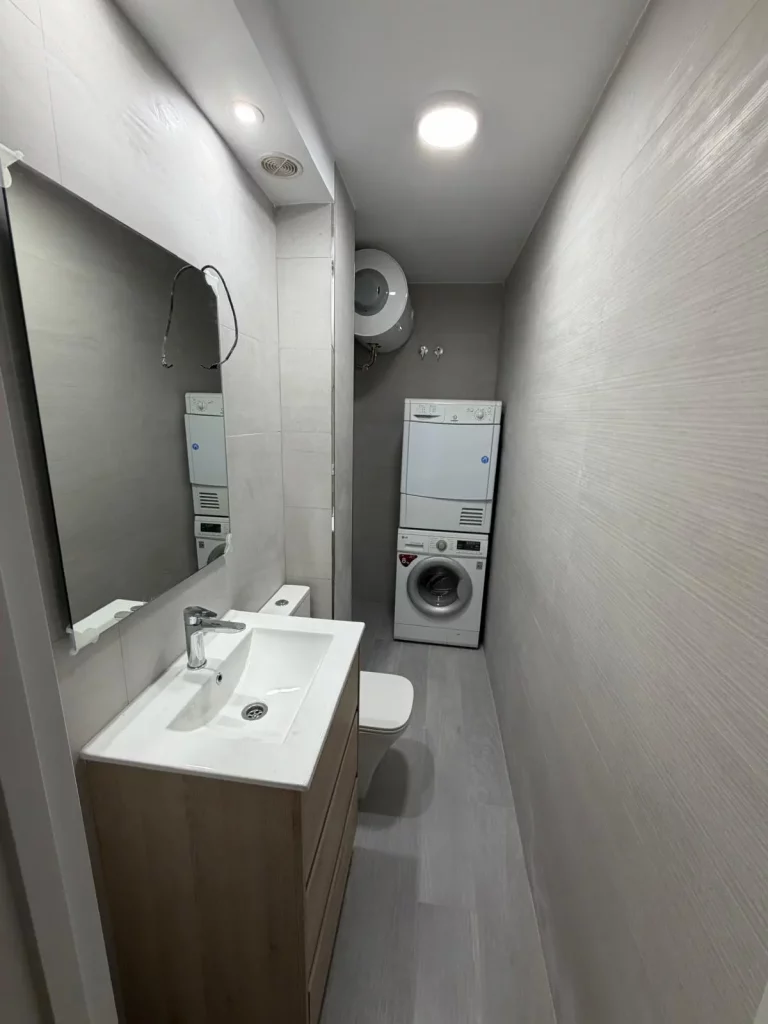 Baño reformado con ducha de obra, mampara de cristal, mueble de lavabo moderno, revestimiento cerámico y acabados contemporáneos. Espacio funcional, luminoso y elegante