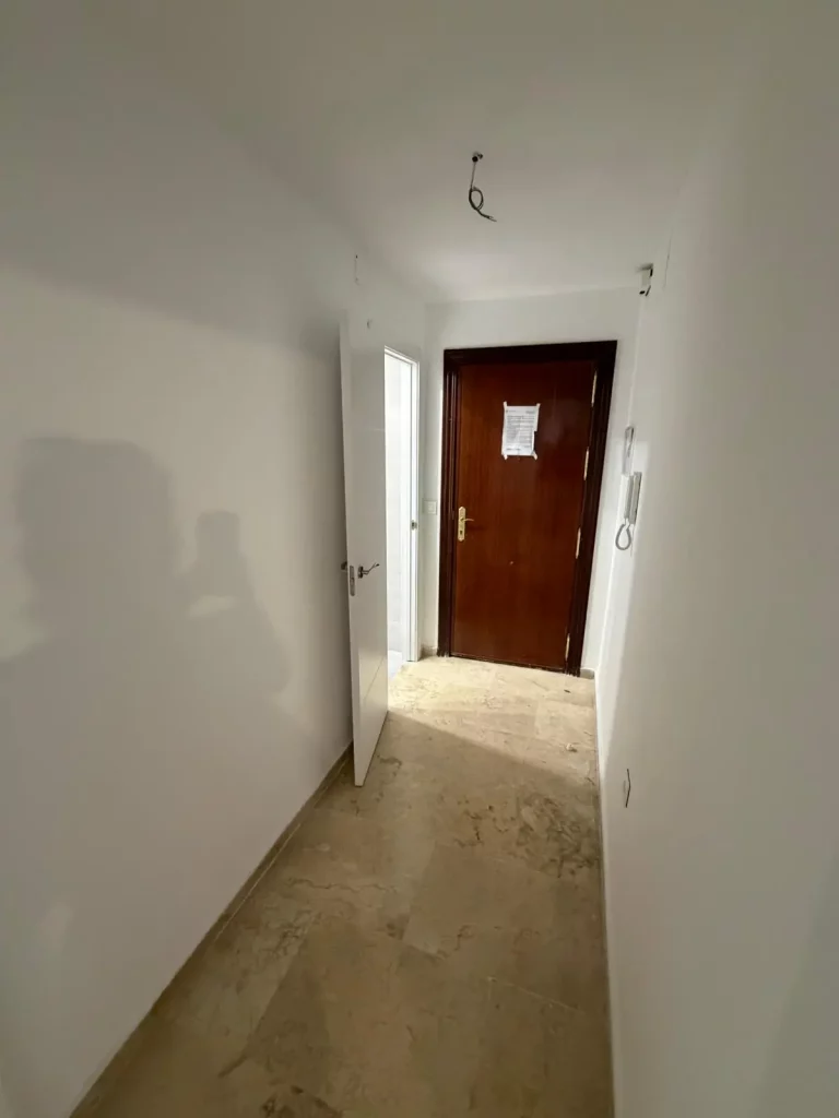 Pasillo distribuidor con acabado moderno, buena iluminación y suelo de alta calidad. Conecta de forma cómoda y eficiente las distintas habitaciones de la vivienda